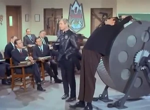 Lutz (front row, second from left) observes Siegfried and Hans's torture demonstration. , posing as a defector, is seated beside him.