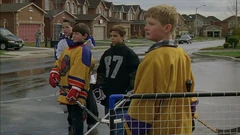 Vlcsnap-2025-10-13-12h09m22s852.png (2.25 MB) Kids playing hockey on the street. In the background, residents rake leaves.