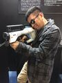 Gen Urobuchi holding an Electromagnetic Induction Rifle prop.