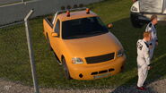 A orange version of the scenery safety truck based on the Ford F-150 of the same generation as it appears in Gran Turismo 7 in the Circuit de Barcelona-Catalunya Rallycross Layout Track in the 1.20 update; a black version also appears in the same track.