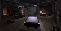The living space of the safehouse, its pool table a unique feature among the five safehouses.