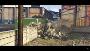 The truck is pushed onto its side, knocking down a wall.