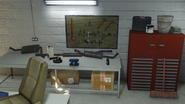 A worktable with 3 large exhaust pipes and catalysts, angle grinder, as well as a large pegboard with several tools.