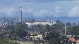 Background view of the warehouse in the opening shot of the second trailer, showing the large "BRIAN'S MARINA" signage on its roof.