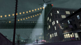 A Police Maverick shines its spotlight on wanted Niko with the Broker Bridge in the background.