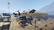 The plane flies through Sandy Shores with Trevor in hot pursuit.