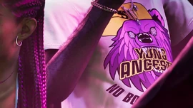 A Yung Ancestor T-shirt worn by an NPC inside the Jack of Hearts strip club, as seen in a screenshot from the Boobie Ike section of the promotional website for Grand Theft Auto VI.