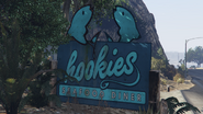 A Hookies sign on the side of highway.