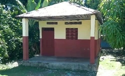 Small concrete structure with a tin roof and shaded porch.