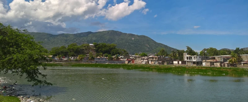 A view across the water toward Petite-Anse, showing the neighborhood’s coastal edge with the northern mountain range rising behind it.