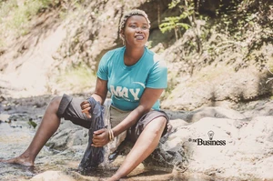 Resident washing clothes in a small stream in the Petit-Harpon area, where natural waterways remain part of daily household routines.