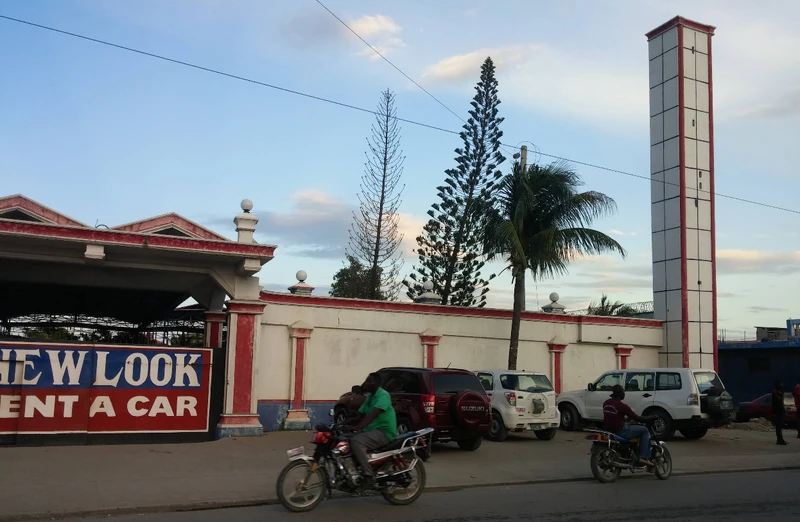 Traffic and mototaxis travel down the RN-3 in Petite-Anse, passing the New Look Rent-A-Car compound, a familiar roadside landmark in the area.