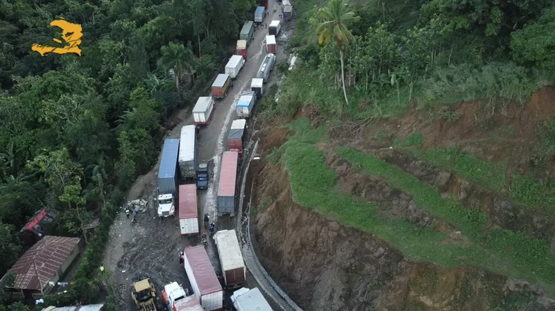 Aerial view of heavy truck traffic stalled along RN-3 in Grand-Gilles following slope failure and road damage, illustrating the corridor’s vulnerability to landslides and its critical role in regional freight movement.