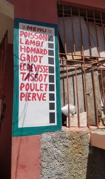 At Vanise Bar-Restaurant, the menu is painted right on the wall, listing local favorites from poisson and lambi to griot and tassot.