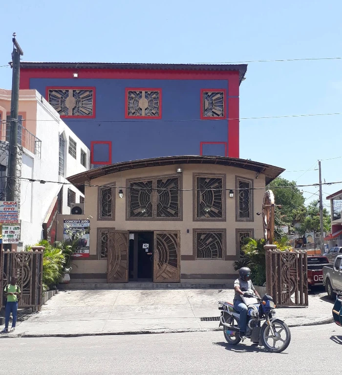 A commercial frontage on Avenue John Brown in Bois-Verna, showcasing intricate iron designs, a common decorative element in the district’s evolving streetscape.