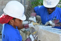 Woman outside her construction training station. “I want to advise other young women like me to not choose only nursing, accounting, or secretarial work. Dare yourself to learn other trades.” Wideline comes from Carrefour-Feuilles.