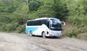 A long-distance passenger bus along a degraded, unpaved stretch of RN-3 in Grand-Gilles