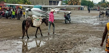 A salt vendor crosses the runway at Port-de-Paix Airport as a small aircraft prepares for landing.