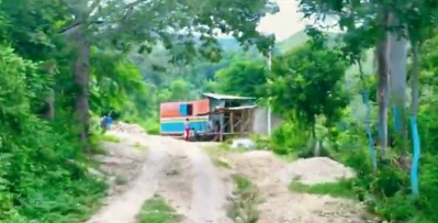 A rural road in Goyavier, where a small shop and a few houses sit along the hillside path.