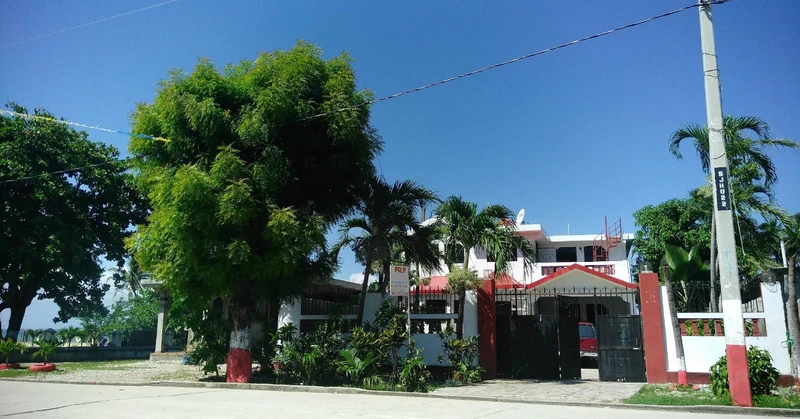 Palm Guest House in Torbeck, offering a quiet, gated setting with palm trees, gardens, and upper-floor guest rooms.