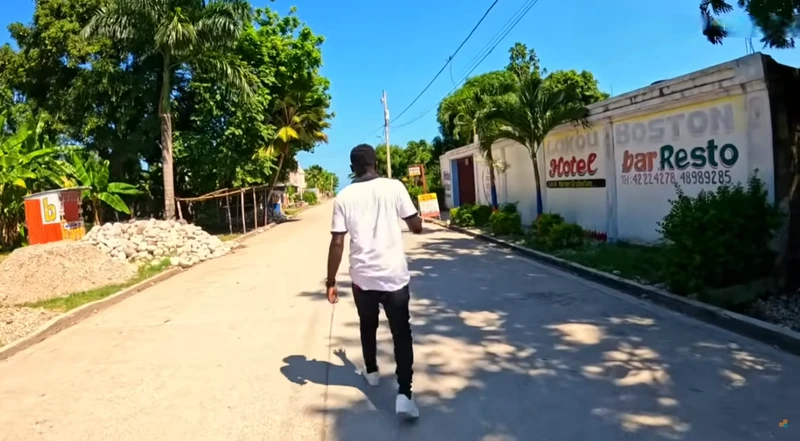 Along Rue Saint-Joseph, a neighborhood stretch leading into the , a passerby walks past Lakou Boston Hotel and Bar-Restaurant