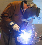 A 21st-century Human welding, the special hood is used so that the person can look into the flame.