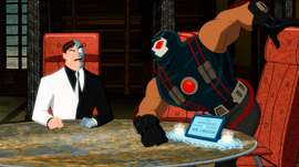 Two-Face, a scarred man in a dress suit, sits at an executive chair while Bane, a large muscular man in a costume, tries to sit in another executive chair that is labelled "In memoriam of Mr