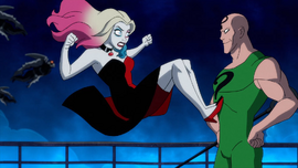 Harley's kick is stopped by Riddler's muscles