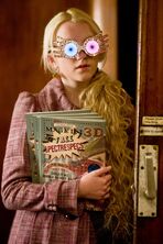 Luna Lovegood verteilt den Klitterer, die Zeitschrift ihres Vaters. Sie hat ihre Geisterbrille auf.