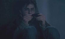 Harry Potter onderzoekt een scherf van de tweewegspiegel gegeven door Sirius Zwarts