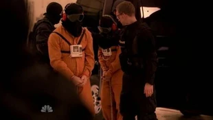 Hooded prisoners lead out of their van. Second prisoner might be Hiro