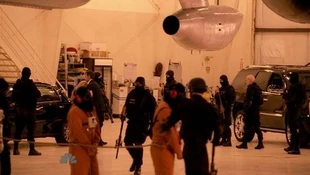 Hooded people being led by guards while Claire and Nathan are in the background. Second and third prisoners are most likely Hiro and Tracy