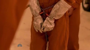 Tracy, shackled, handcuffed and wearing gloves