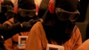 A hooded fugitive is being readied by a guard. Note:His/her hair is slipping out of his/her hood. Possibly Tracy