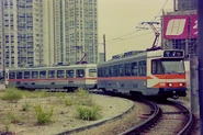 九鐵橙白色塗裝的輕鐵第一期列車正拖着橙白色塗裝的輕鐵第二期列車
