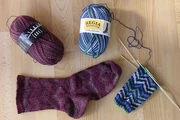 knitting -- yarn, a finished sock and another project in process