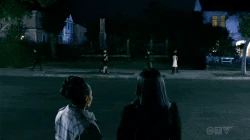 Annalise y Tegan pasan por la calle donde se encuentran los restos de la Mansión Keating.