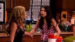 Carly gripping Sam's wrist and keeps the grip through pulling the pizza out of Sam's mouth