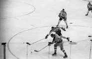 Don McKenney shoots past Canadiens Tom Johnson during the Bruins 4-2 win on October 12, 1958. McKenney is wearing the new gold pants introduced in 1958.