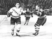 Bruins Warren Godfrey and Rangers Lou Fontinato battle for the puck while Hal Laycoe looks on, March 2, 1955.