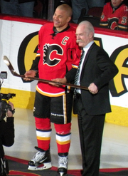 Iginla and McDonald jointly hold a gold stick as they smile for a photographer (off camera).