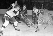  and  battle for the puck while  and  look on, January 19, 1957.