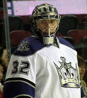 An ice hockey goaltender wearing a white jersey with a silver crown on the front.