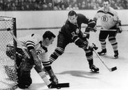 Bruins Eddie Johnston clears the puck away from Leafs #12 Ron Stewart while Leo Boivin watches, March 3, 1963.