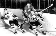 Leafs Eddie Shack jumps between Bruins #22 Irv Spencer and Jean-Guy Gendron, January 26, 1963.