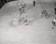 Bruins Frank Brimsek makes a save in a 2-1 win against the Rangers while #4 Herb Cain looks, November 15, 1941.