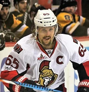 man with mustache and beard wearing a white ice hockey uniform