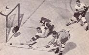 Wayne Connelly shooting on Hank Bassen while Howie Young looks on in 1961-62 season action.