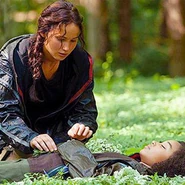 Katniss układająca kwiaty na ciele dziewczynki.