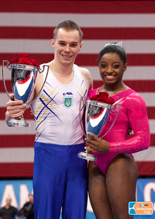 Biles (right) with her American Cup, and the male winner Oleg Verniaiev (UKR)